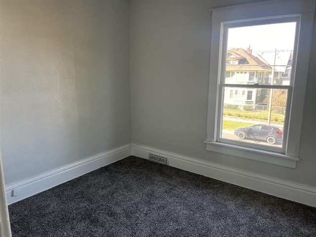 empty room with baseboards, visible vents, and dark carpet