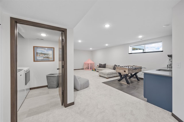 living area featuring light carpet, baseboards, washer and dryer, and recessed lighting