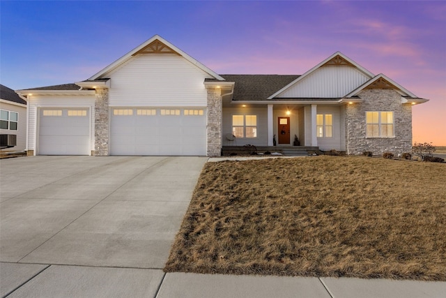 view of front of house with a garage, stone siding, driveway, and a porch