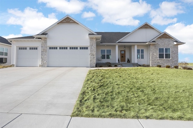 craftsman-style home with a garage, stone siding, driveway, and a front yard