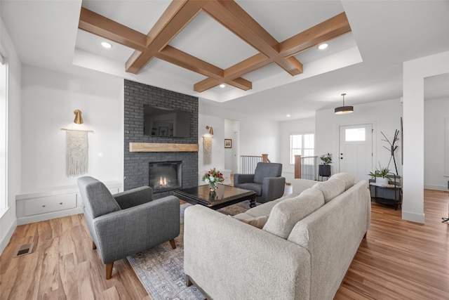 living room with a fireplace, light wood-type flooring, coffered ceiling, and visible vents