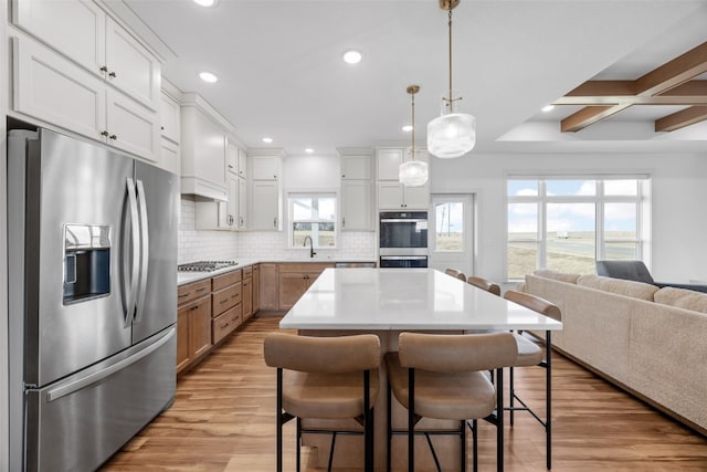 kitchen featuring stainless steel appliances, light wood-type flooring, backsplash, and a kitchen breakfast bar