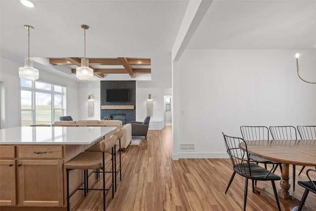 kitchen with coffered ceiling, a fireplace, visible vents, baseboards, and light wood finished floors