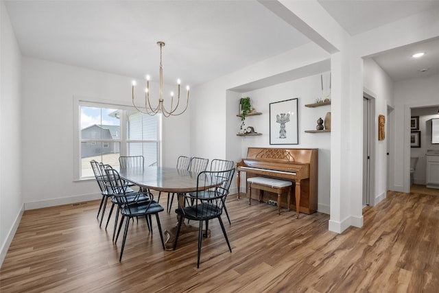 dining room with a notable chandelier, baseboards, and wood finished floors