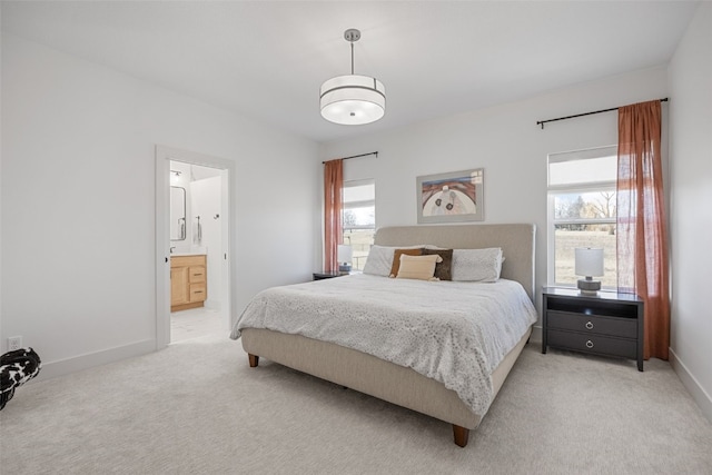 bedroom with light carpet, connected bathroom, and baseboards