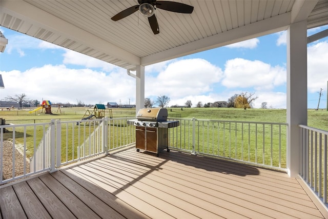 deck featuring a yard, a rural view, a playground, and a grill