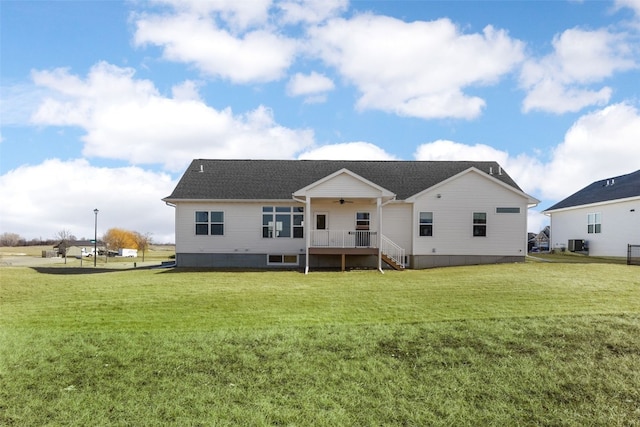 rear view of house featuring central air condition unit, a ceiling fan, and a yard