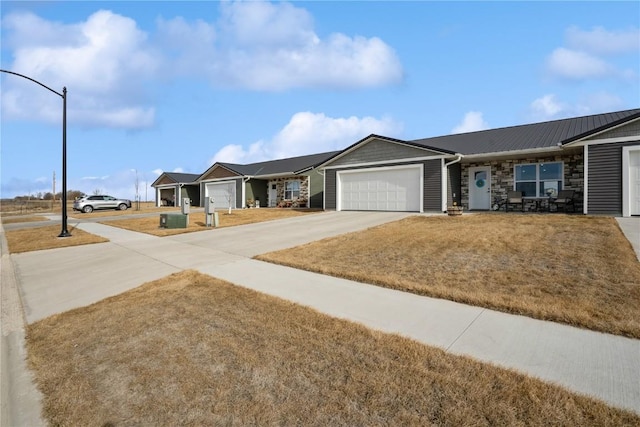 ranch-style home with a garage, stone siding, and concrete driveway