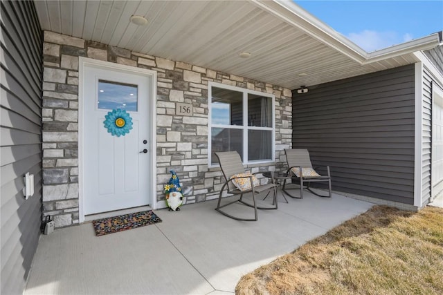 view of exterior entry featuring stone siding and a porch