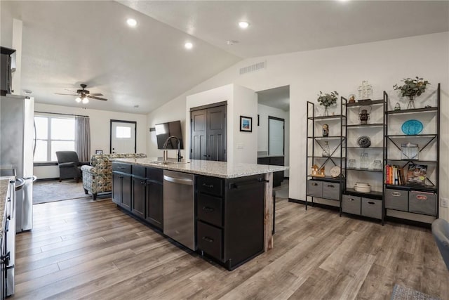 kitchen featuring light wood finished floors, visible vents, lofted ceiling, dark cabinets, and stainless steel appliances