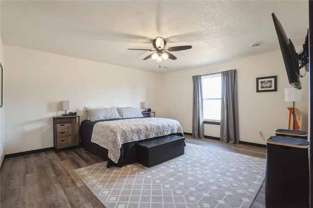 bedroom with a ceiling fan, a textured ceiling, baseboards, and wood finished floors