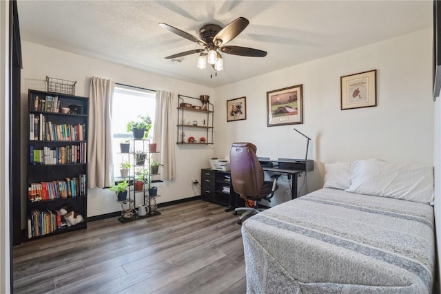 bedroom featuring ceiling fan, baseboards, and wood finished floors