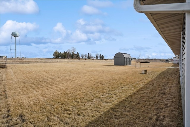 view of yard with a shed, a rural view, and an outbuilding