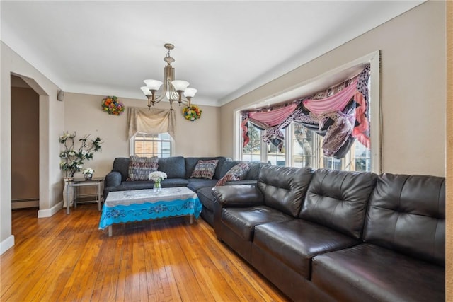 living room featuring baseboards, a chandelier, arched walkways, hardwood / wood-style flooring, and a baseboard heating unit