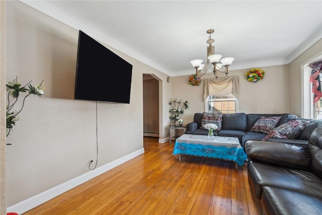 living room with light wood finished floors, baseboards, a chandelier, arched walkways, and a baseboard heating unit