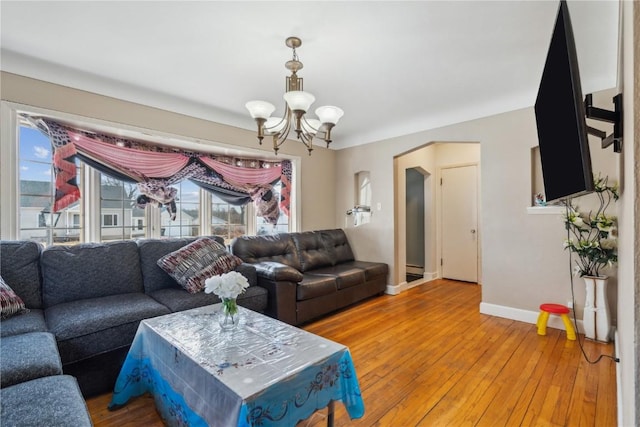 living area with light wood-style floors, baseboards, arched walkways, and a chandelier