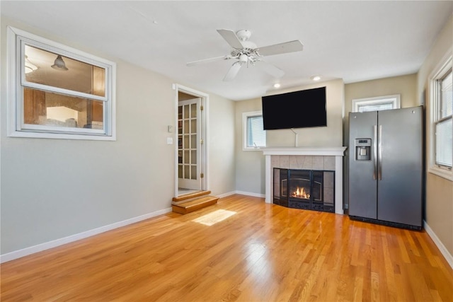 unfurnished living room featuring a fireplace, wood finished floors, a ceiling fan, and baseboards