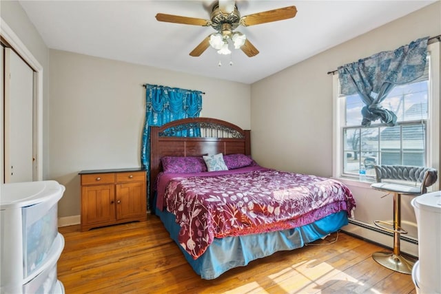 bedroom with baseboards, ceiling fan, baseboard heating, light wood-style floors, and a closet