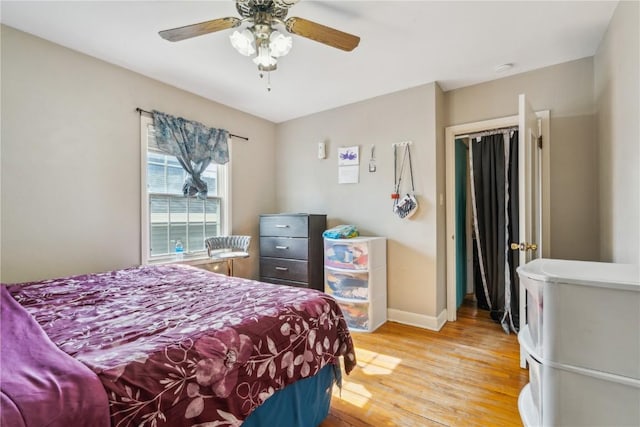 bedroom with ceiling fan, light wood finished floors, and baseboards