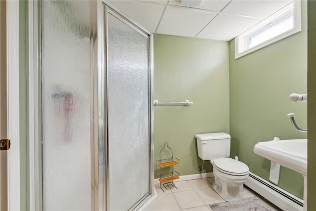 bathroom with toilet, a shower stall, baseboard heating, and tile patterned floors