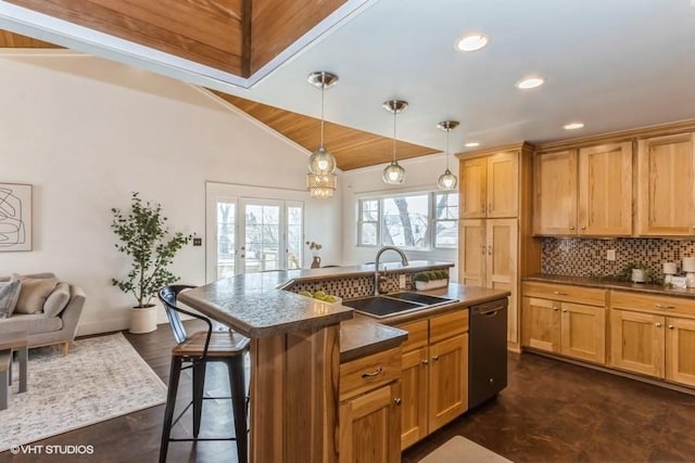 kitchen with tasteful backsplash, dark countertops, a sink, dishwasher, and a kitchen bar