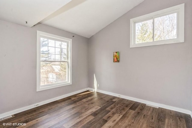 spare room with vaulted ceiling, wood finished floors, visible vents, and baseboards