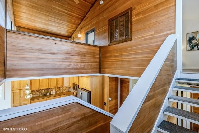 staircase featuring vaulted ceiling, wooden ceiling, and wooden walls