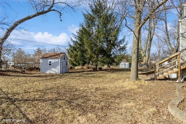 view of yard with stairs, an outdoor structure, fence, and a storage unit