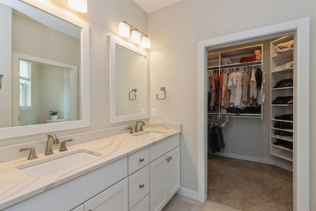 bathroom featuring a sink, a spacious closet, and double vanity