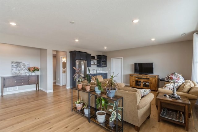 living room featuring recessed lighting, baseboards, visible vents, and light wood finished floors