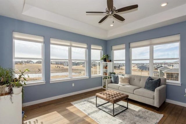 sunroom / solarium with ceiling fan and a tray ceiling