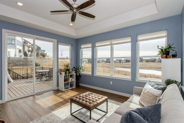 sunroom / solarium with ceiling fan and a tray ceiling