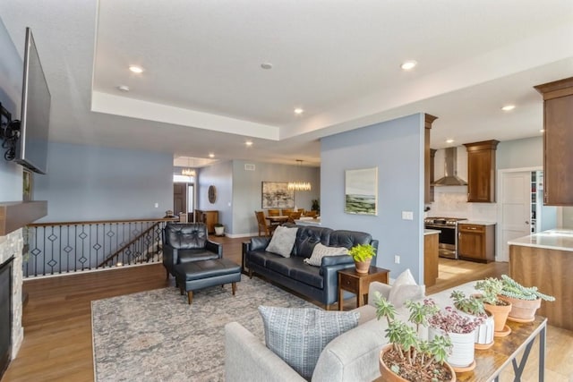 living room featuring light wood-type flooring, a raised ceiling, and recessed lighting