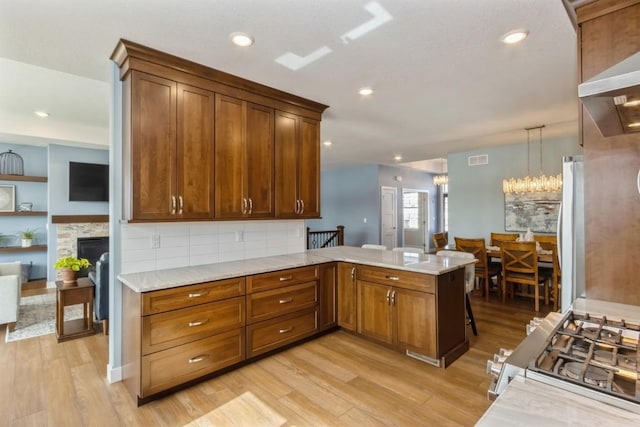 kitchen with a peninsula, light wood-style floors, visible vents, and freestanding refrigerator