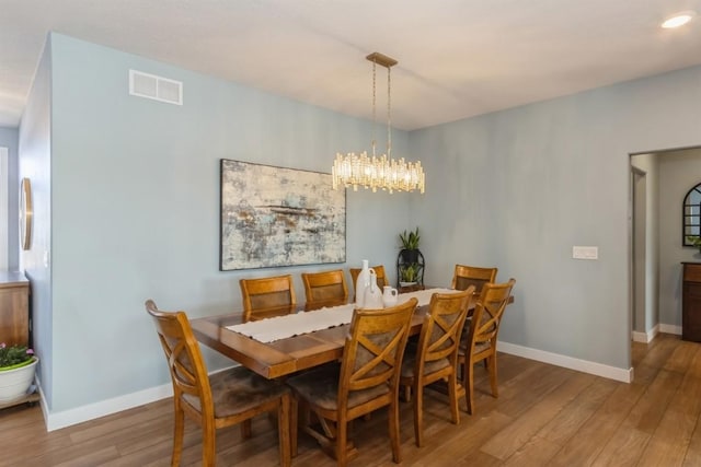 dining area featuring a notable chandelier, wood finished floors, visible vents, and baseboards