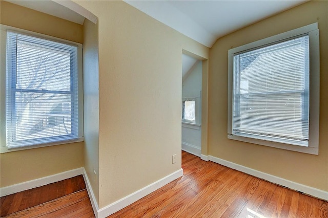 hall featuring light wood-type flooring, baseboards, and arched walkways