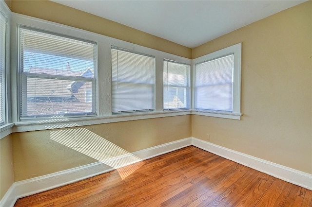 spare room featuring wood finished floors, a wealth of natural light, and baseboards