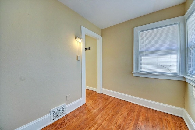 empty room featuring light wood finished floors, visible vents, and baseboards