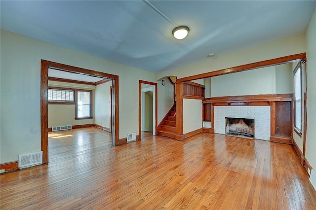 unfurnished living room featuring stairs, visible vents, and light wood-style floors