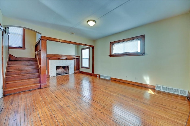 unfurnished living room with visible vents, a fireplace, hardwood / wood-style floors, and stairs