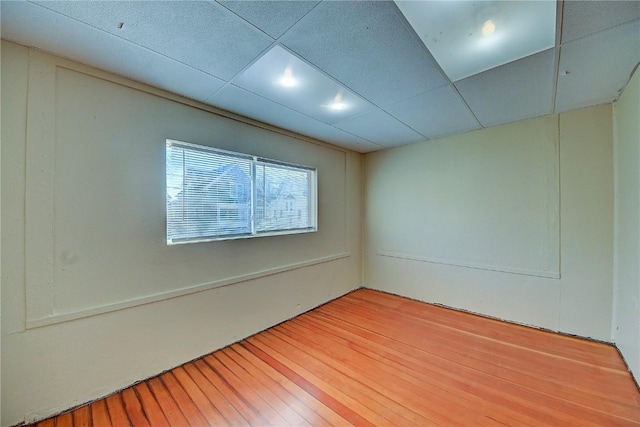 unfurnished room with light wood finished floors and a drop ceiling