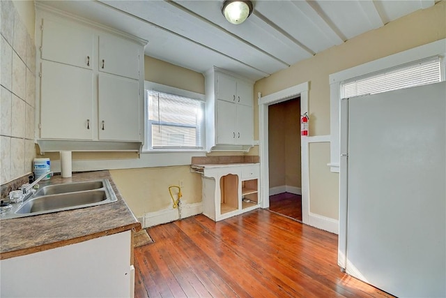 kitchen with baseboards, wood-type flooring, beamed ceiling, white fridge, and a sink