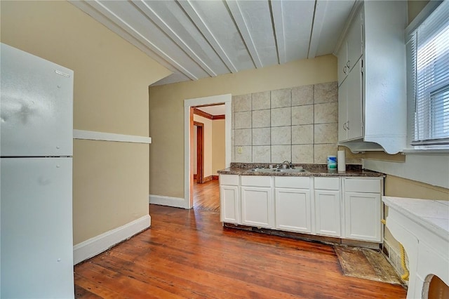 kitchen with dark wood finished floors, decorative backsplash, white cabinetry, a sink, and baseboards