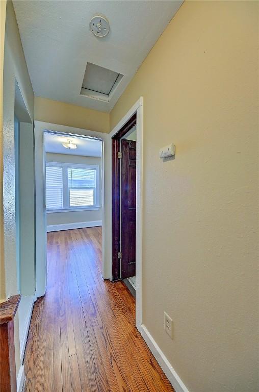 hall featuring attic access, baseboards, and hardwood / wood-style floors