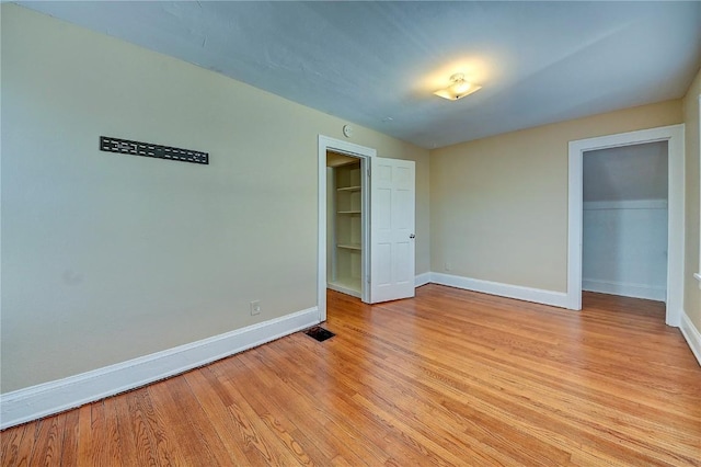 unfurnished bedroom with light wood finished floors, visible vents, baseboards, and a closet