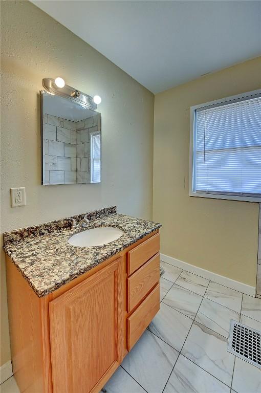 bathroom with marble finish floor, vanity, visible vents, and baseboards