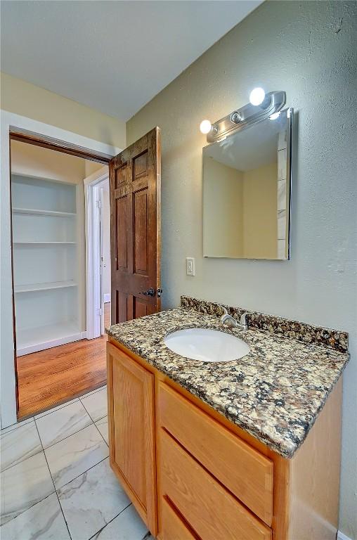 bathroom featuring built in shelves, marble finish floor, and vanity