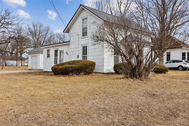 view of side of property with a garage, a yard, and metal roof