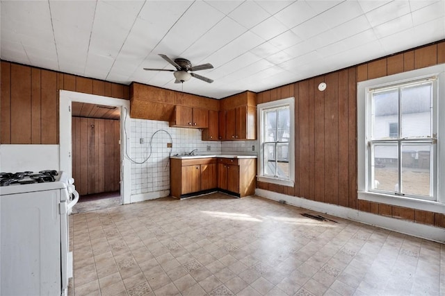 kitchen featuring ceiling fan, brown cabinets, light countertops, white gas stove, and a sink