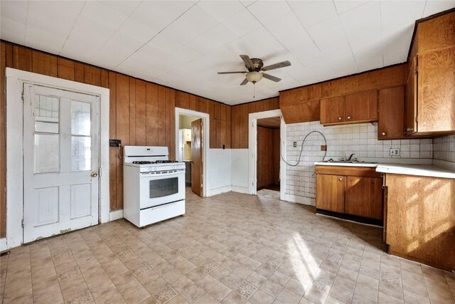 kitchen with light countertops, brown cabinets, a ceiling fan, and white range with gas cooktop